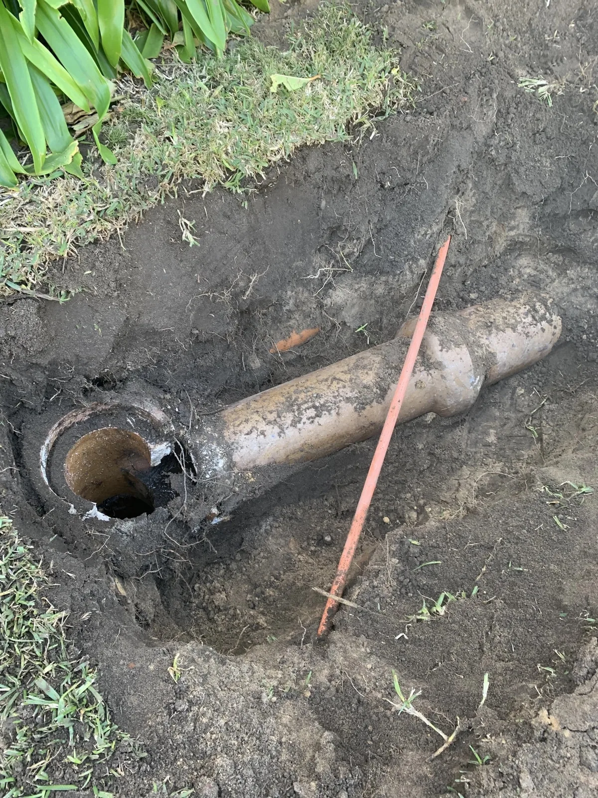 A damaged section of drain pipe exposed in an excavation